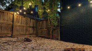 A backyard with a wooden fence, a tree, and a table with a disc golf setup. - Premier Access Zilker Park & SoCo (Austin)