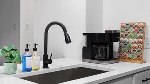 A kitchen with a modern faucet, a coffee maker, and a soap dispenser. - Premier Access Zilker Park & SoCo (Austin)