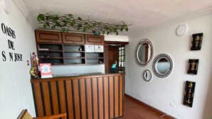 Una habitación acogedora con un sofá de madera, una pequeña mesa redonda y una zona de cocina con encimera y armarios.