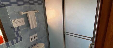 A bathroom with a toilet, sink, and shower area.