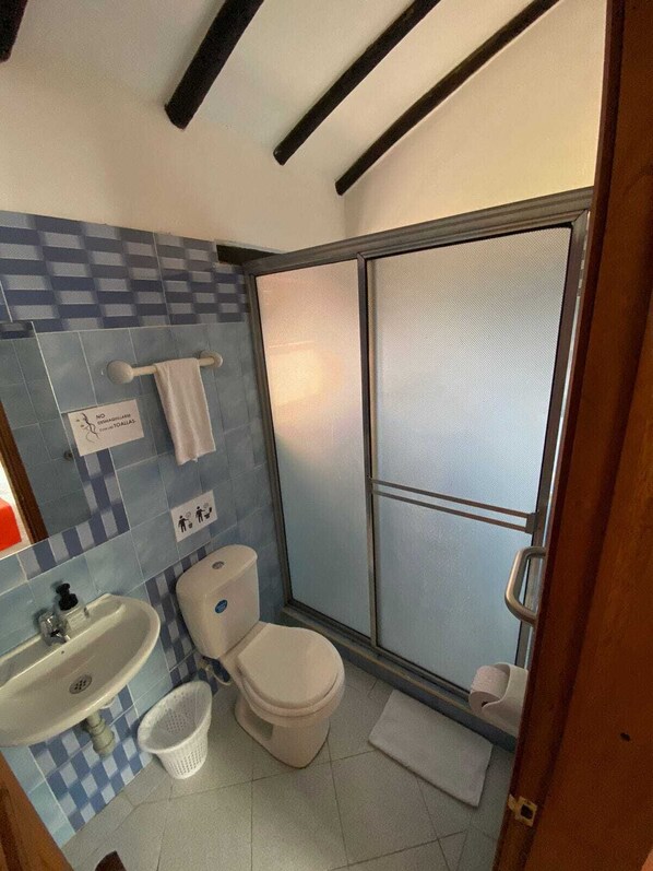 Une salle de bain comprenant des toilettes, un lavabo et un espace douche.