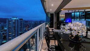 A modern balcony with a city view, a dining area with a table set for two, and a decorative orchid arrangement. - Perfect apartment in the best building on the waterfront with an unobstructed view of the incredible sea! (José Menino Santos)