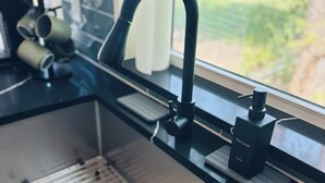 A kitchen with a modern faucet, a dish soap dispenser, and a window with a view of greenery. - New 1B1B on 3 acres in Crowley, TX. Suburban tranquility, urban accessibility. (Crowley)