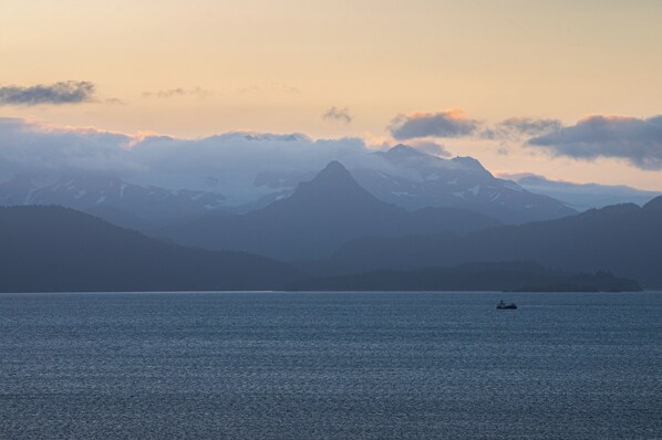 A calm lake with a boat in the distance, surrounded by mountains and a clear sky. - Stunning Oceanfront Log Home w/Glacier & Spit View (Homer)