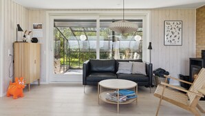 Un salon moderne avec un canapé en cuir noir, une table basse ronde, un meuble en bois et une cheminée.