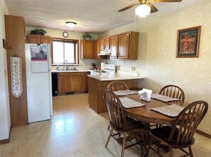 A kitchen with wooden cabinets, a dining table with chairs, a ceiling fan, and a clock on the wall. - Welcome!  Living rm, Family rm, 2 Bathrm w/ shower (DeForest)