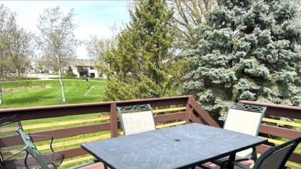 A deck with a table and chairs, overlooking a grassy area and trees. - Welcome!  Living rm, Family rm, 2 Bathrm w/ shower (DeForest)