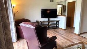A living room with a sofa, a television on a stand, a coffee table, and a door leading to another room. - Welcome!  Living rm, Family rm, 2 Bathrm w/ shower (DeForest)
