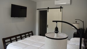Une chambre d’hôtel équipée d’un lit, d’un téléviseur fixé au mur, d’une lampe de chevet et d’une porte coulissante.