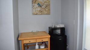 A kitchen with a wooden table, a microwave, and a painting of a bird on a branch.