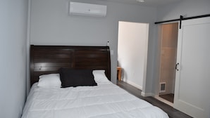 A bedroom with a wooden headboard, a white bedspread, and a white door.