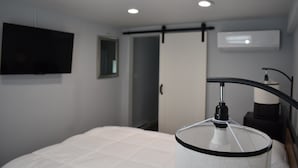 Une chambre d’hôtel moderne équipée d’un lit, d’un téléviseur fixé au mur, d’une lampe de chevet et d’un appareil de climatisation.