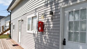 Une maison blanche avec une porte d’entrée, une boîte aux lettres et un poteau d’incendie.