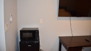 A compact kitchen area with a microwave and a television mounted on the wall.