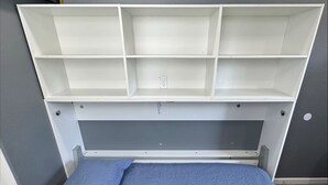 A bed with a blue mattress and a matching blue pillow, a white headboard with shelves, and a grey wall. - Micro Studio With Outdoor Space Near Nike & Intel (Beaverton)