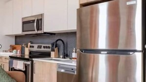 A modern kitchen with stainless steel appliances, wooden cabinets, and a built-in microwave.