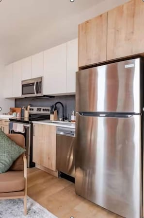 A modern kitchen with stainless steel appliances, wooden cabinets, and a built-in microwave.
