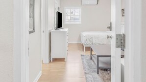 Een slaapkamer met een bed, een bureau, een stoel, een televisie en een plafondventilator.