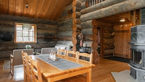 A log cabin interior with a dining area, sofa, fireplace, and a television. - Comfy Cabin Retreat Close To The Rukatunturi Ski Slopes (Ruka)