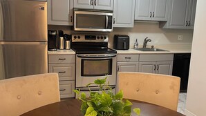 A modern kitchen with stainless steel appliances, white cabinets, and a dining table with chairs.