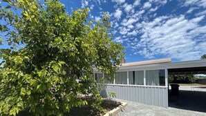 Un bâtiment doté d’un espace de stationnement couvert, d’un arbre devant et d’un ciel dégagé.
