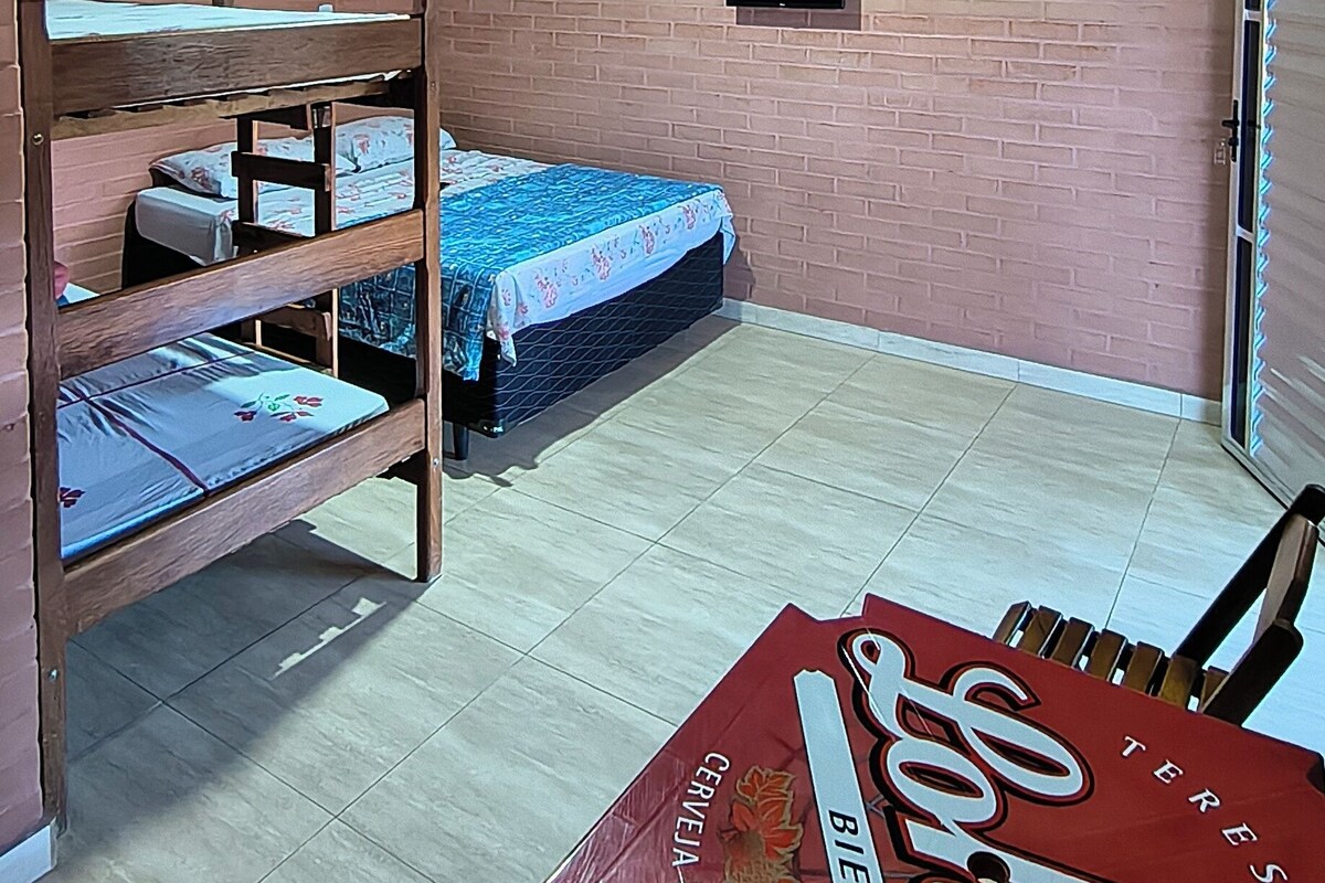 A room with a bunk bed, a television mounted on the wall, and a table with a beer advertisement.