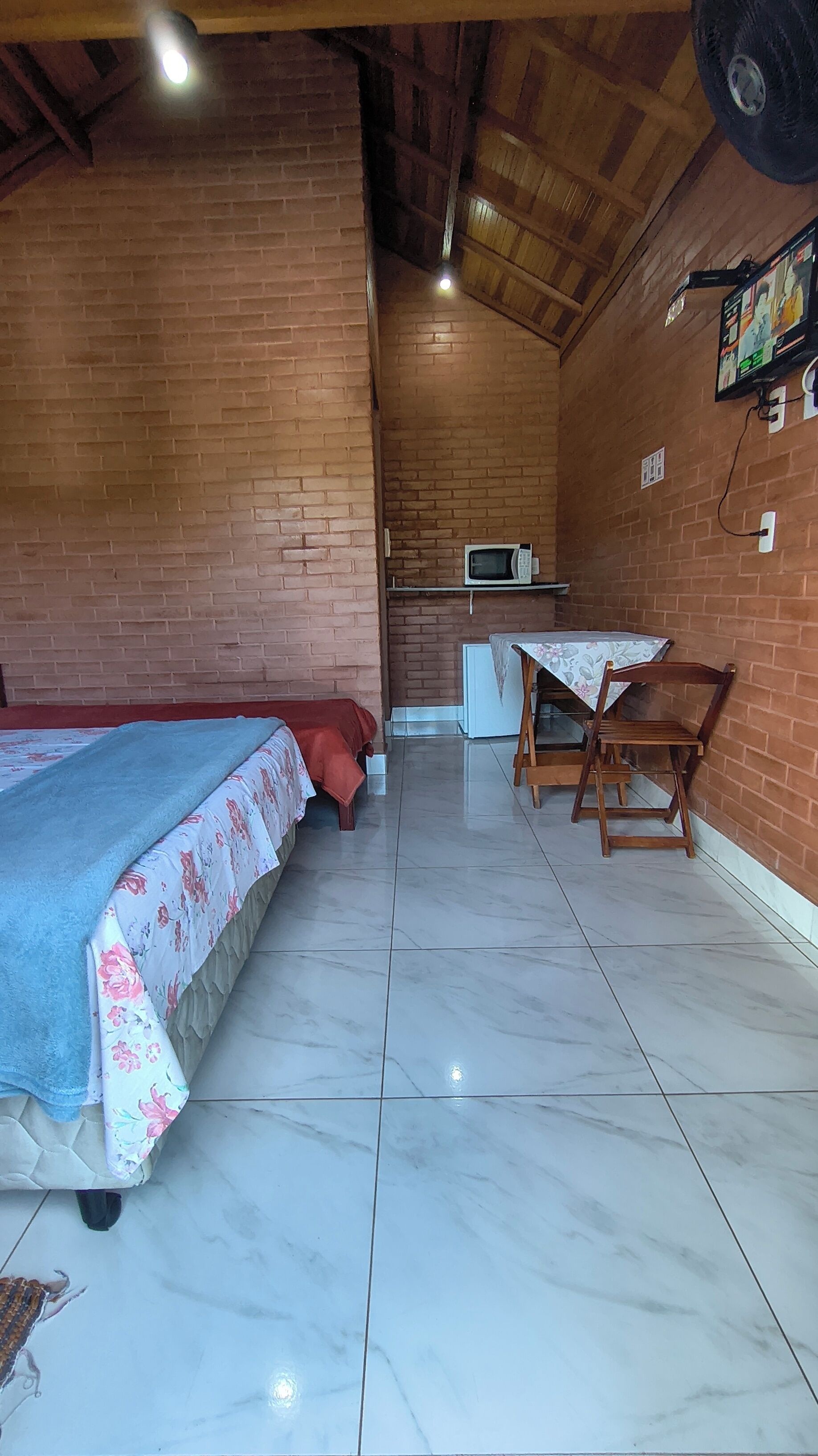 Um quarto com uma cama, uma mesa com cadeiras, micro-ondas e frigorífico.