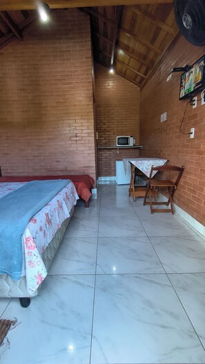 A room with a bed, a table with chairs, a microwave, and a refrigerator.