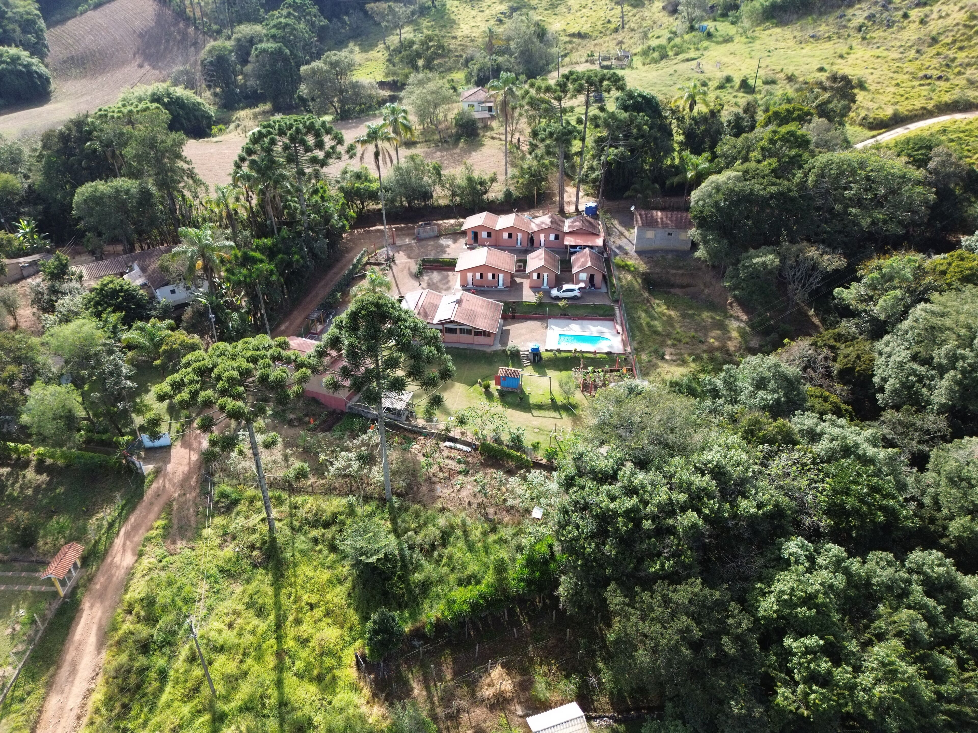 Zona residencial con varias casas, una piscina y un camino de tierra.