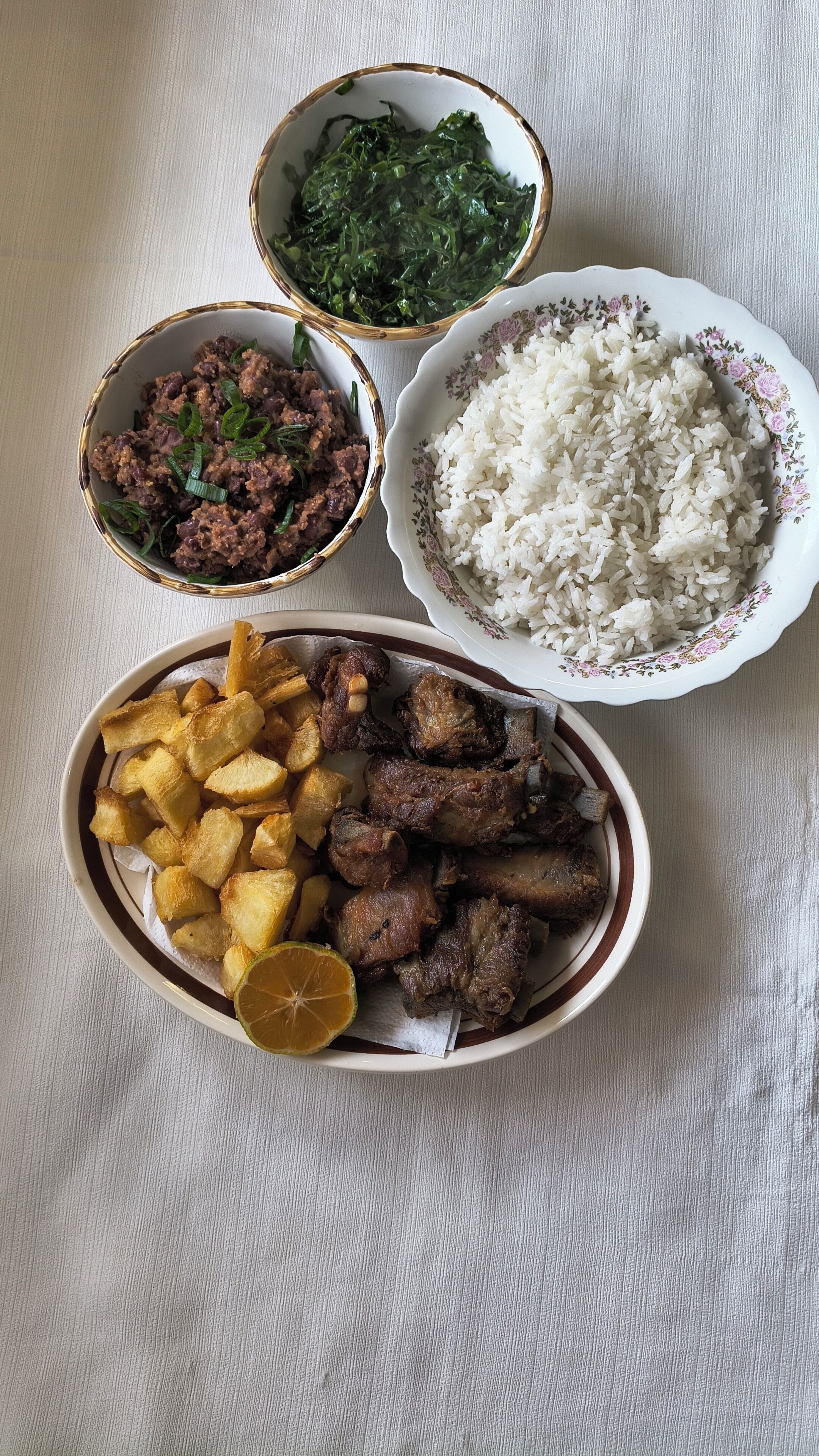 Una mesa con cuatro cuencos que contienen diferentes platos, como arroz, carne y vegetales verdes.