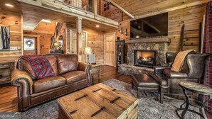 A cozy cabin interior with a fireplace, leather furniture, and wooden walls. - Blue Ridge Shadows Lodge: Escape to the serene Blue Ridge Mountains (Morganton)
