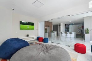 A modern living room with a large flat-screen TV, comfortable seating, and a glass partition leading to a dining area. - Beachfront Luxury Condo w/ Infinity Pool & Hot Tub (Playa Encanto)
