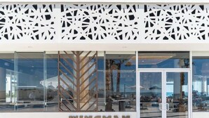 A building facade with a modern design, featuring a geometric pattern on the upper part and a glass entrance with the name 'WINGMAN' displayed prominently.