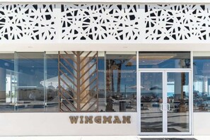 A modern building facade with a geometric pattern, a glass entrance, and the name 'WINGMAN' prominently displayed. - Beachfront Luxury Condo w/ Infinity Pool & Hot Tub (Playa Encanto)