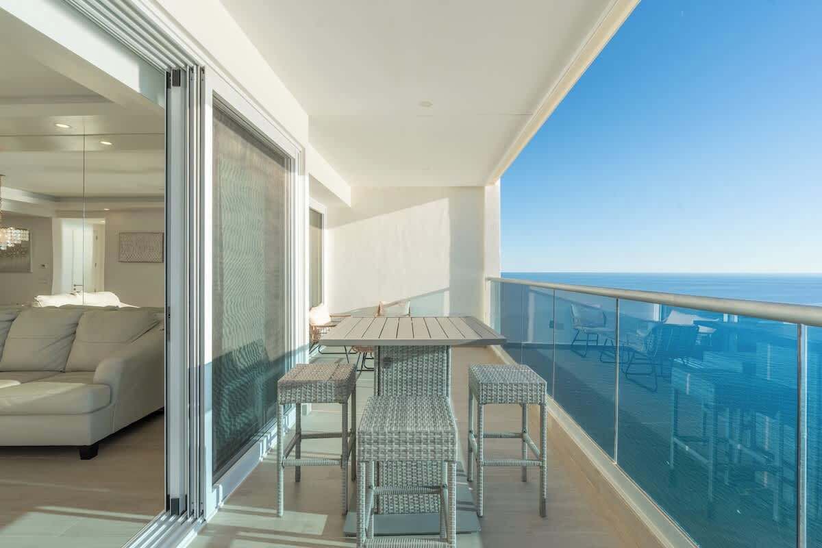 Ein Balkon mit Esstisch und Stühlen, einer Sitzecke und Blick aufs Meer.