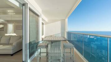 Ein Balkon mit Esstisch und Stühlen, einer Sitzecke und Blick aufs Meer.