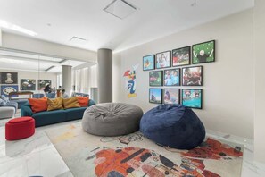 A modern living room with a blue sofa, red ottoman, and a large bean bag.