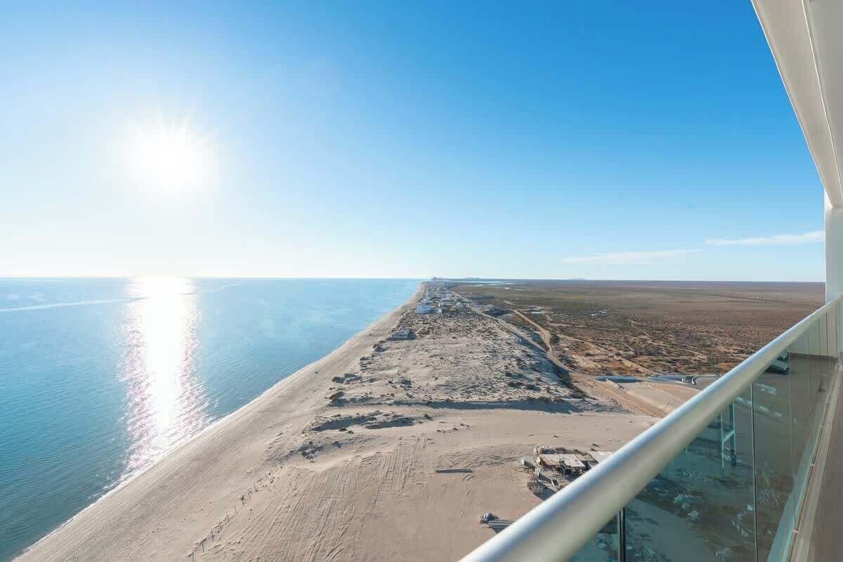 Une vue sur la côte depuis un balcon, avec un ciel dégagé et une mer calme.