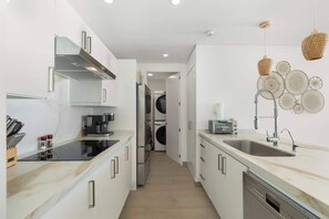 A modern kitchen with a central island, built-in appliances, and a dishwasher. - Beachfront Luxury Condo w/ Infinity Pool & Hot Tub (Playa Encanto)