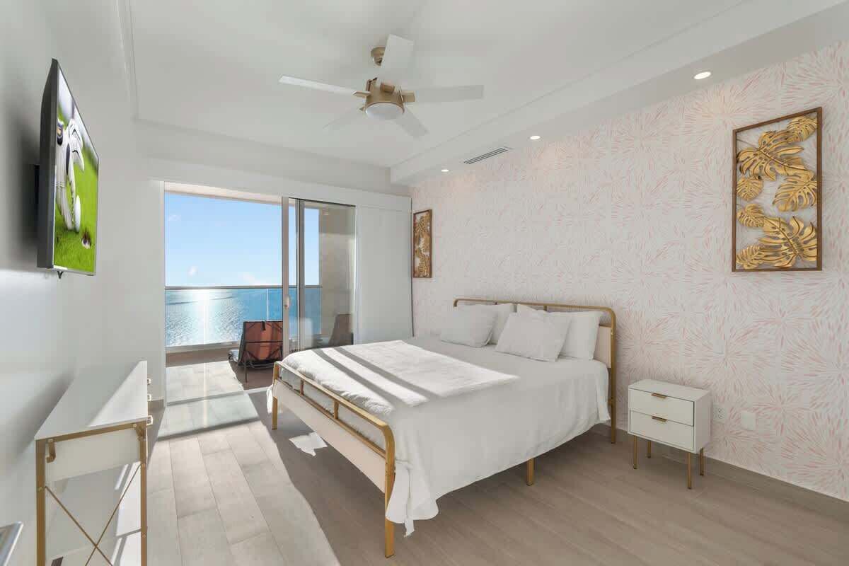 Un dormitorio moderno con cama, mesita de noche y vista al mar.
