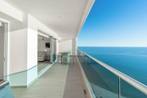 A balcony with a glass railing overlooking the sea.