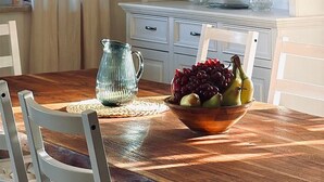 A dining area with a wooden table, a bowl of fruit, a pitcher, and a white cabinet with drawers. - Vacation home Fringaluna with private pool in Übersee am Chiemsee (Übersee)