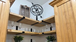 Una cucina con mobili in legno, una sfera geografica decorativa e diverse calici da vino su mensole.