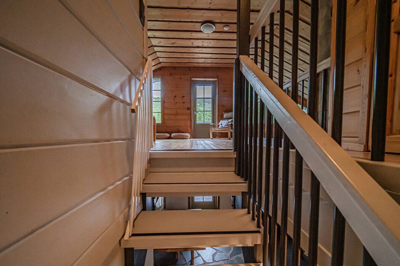 A wooden staircase leading to a room with a door and a window.