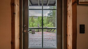 A wooden door with a glass panel leading to an outdoor deck with a wooden floor and a metal railing.