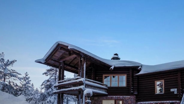 Una cabaña de madera con balcón y techo cubierto de nieve.