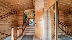 Interior de madera con una escalera que lleva a un segundo piso, una puerta de madera y una planta pequeña.