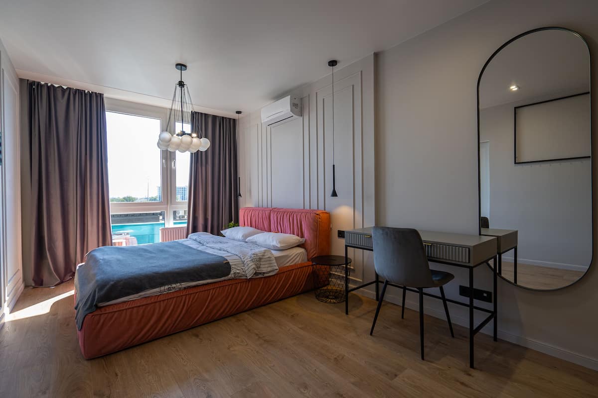 A modern bedroom with a bed, desk, chair, and a large mirror.