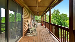 A wooden deck with a railing, a rocking chair, and a table. - Pet Friendly, Views, Lake Lure Access, Wi Fi - My Mountain Paradise (Lake Lure)