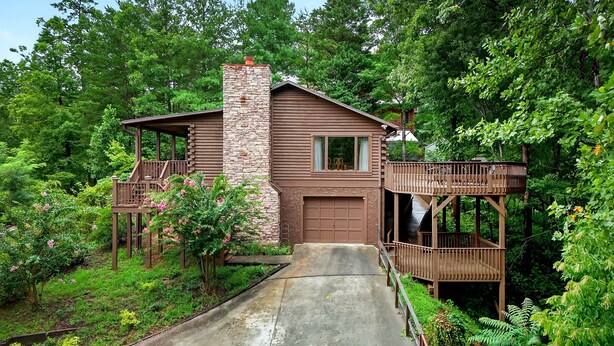 A cabin with a stone chimney, a garage, and a wooden deck. - Pet Friendly, Views, Lake Lure Access, Wi Fi - My Mountain Paradise (Lake Lure)
